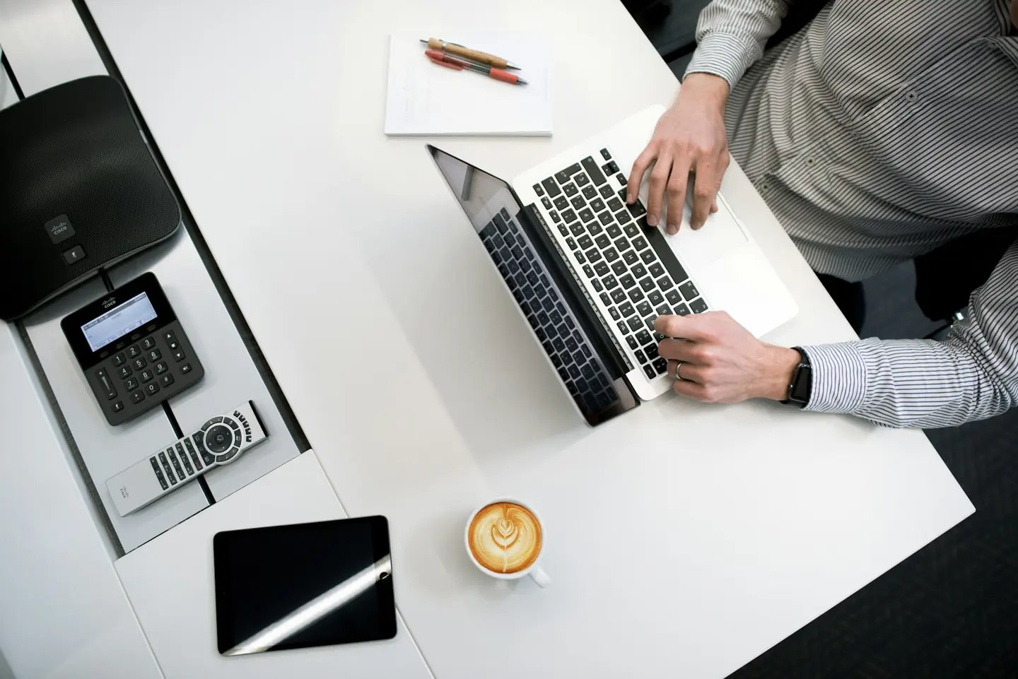 Overhead view of a desk with a laptop, notebook and phone